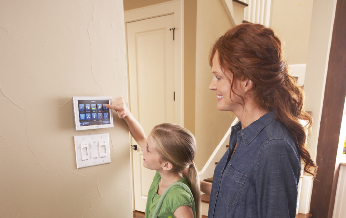 A mom and her daughter changing the thermostat in their home.