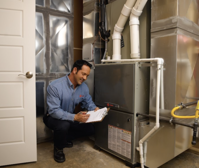 Technician taking notes in front of a heating unit
