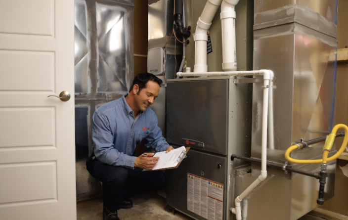 Technician taking notes in front of a heating unit